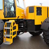 Yellow and black articulated industrial dump truck with large tires and metal access ladder on asphalt surface