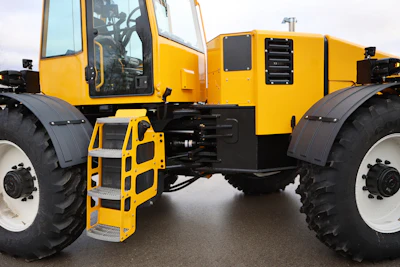 Yellow and black articulated industrial dump truck with large tires and metal access ladder on asphalt surface