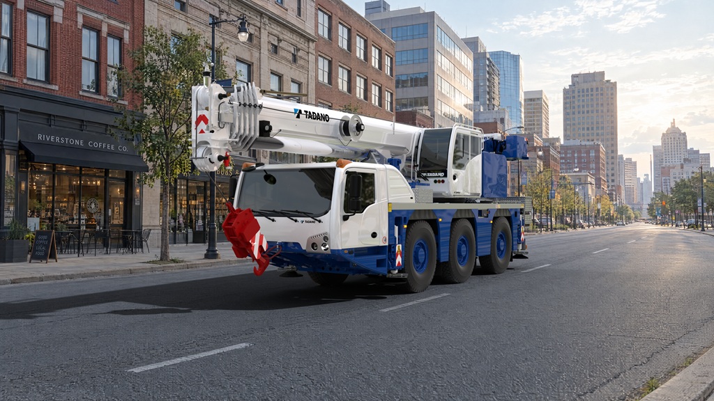 White and blue Tadano mobile crane truck parked on urban street with city buildings in background