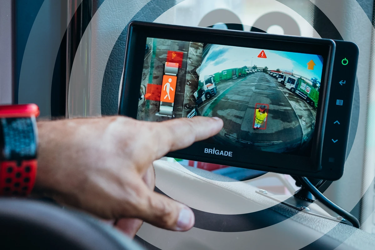 Person holding Brigade dashcam displaying wide-angle vehicle footage with traffic scene